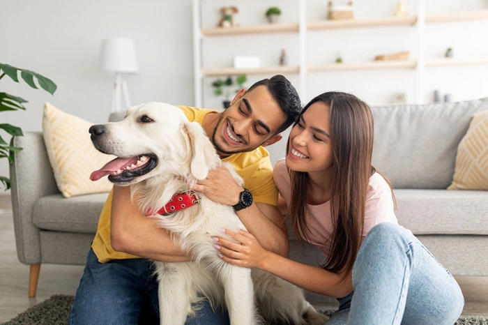 Priscila and Cesar with golden retriever in front of a couch